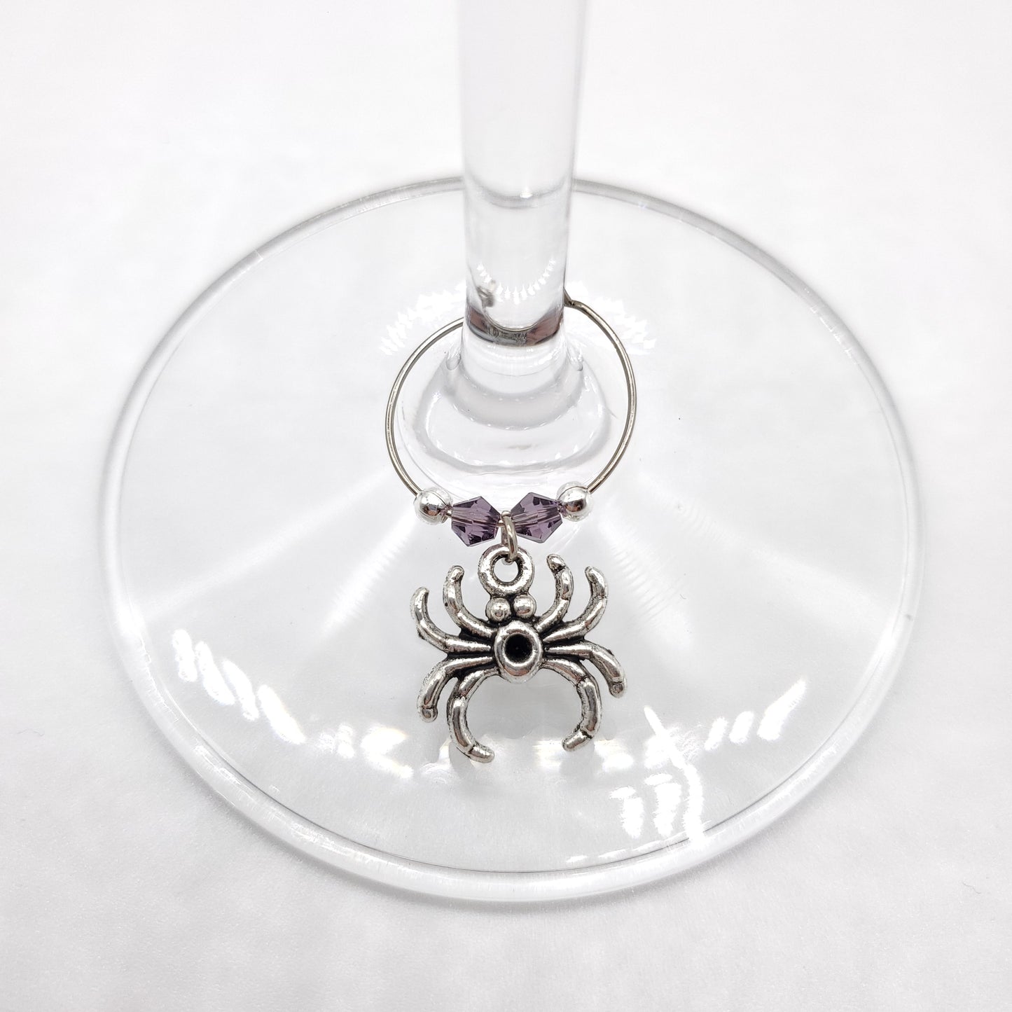 Wine glass charm with spider design on a white background