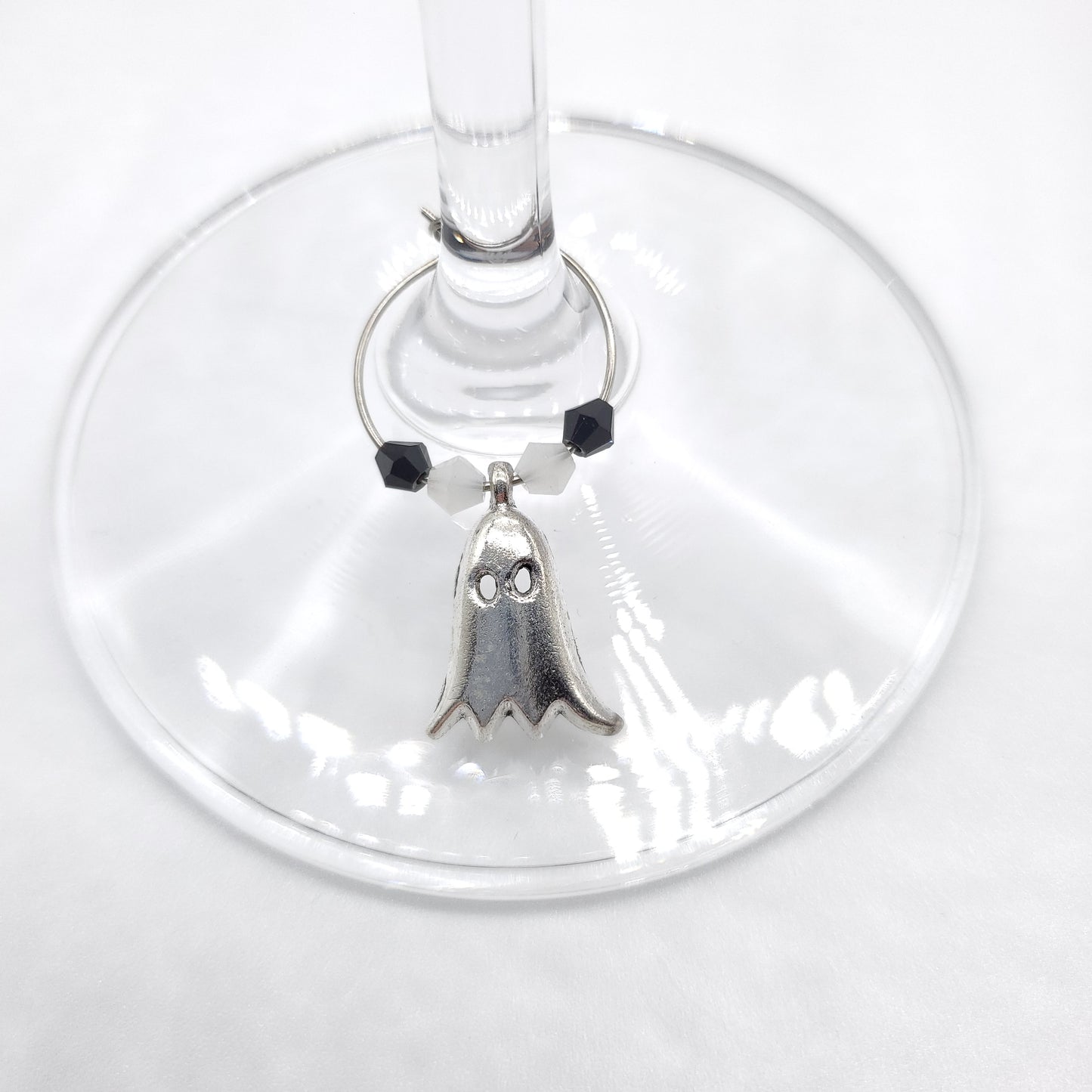 Ghost wine charm with white and black beads displayed on wine glass stem