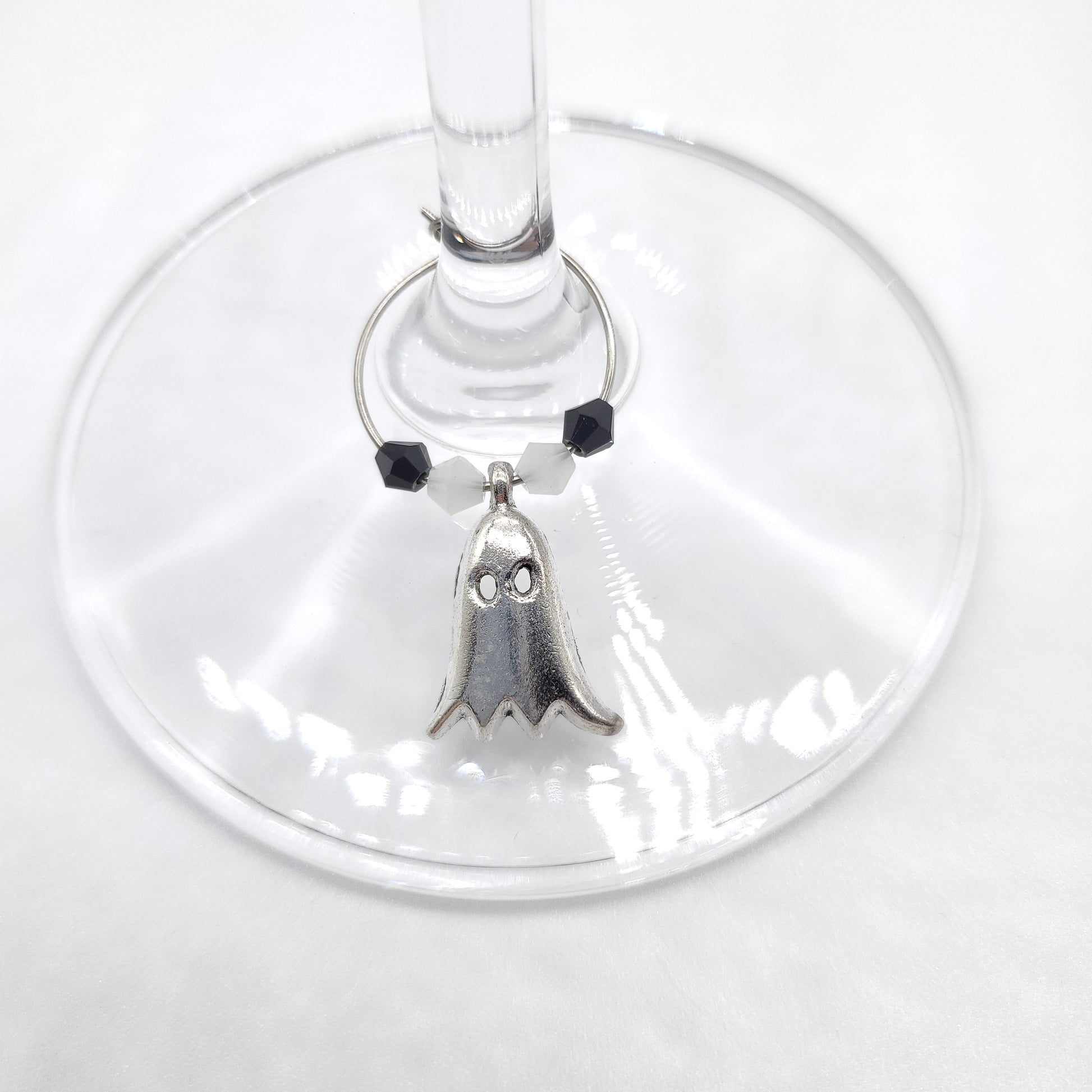 Ghost wine charm with white and black beads displayed on wine glass stem