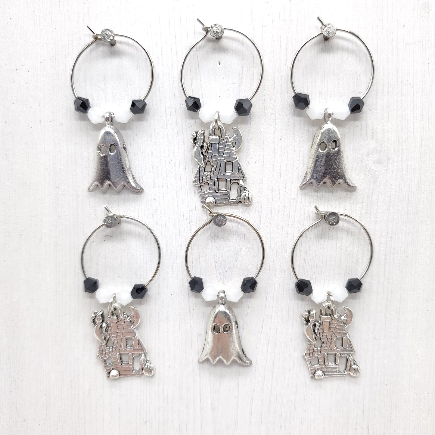 Set of silver wine glass charms with various designs, and with white and black beads on a white background