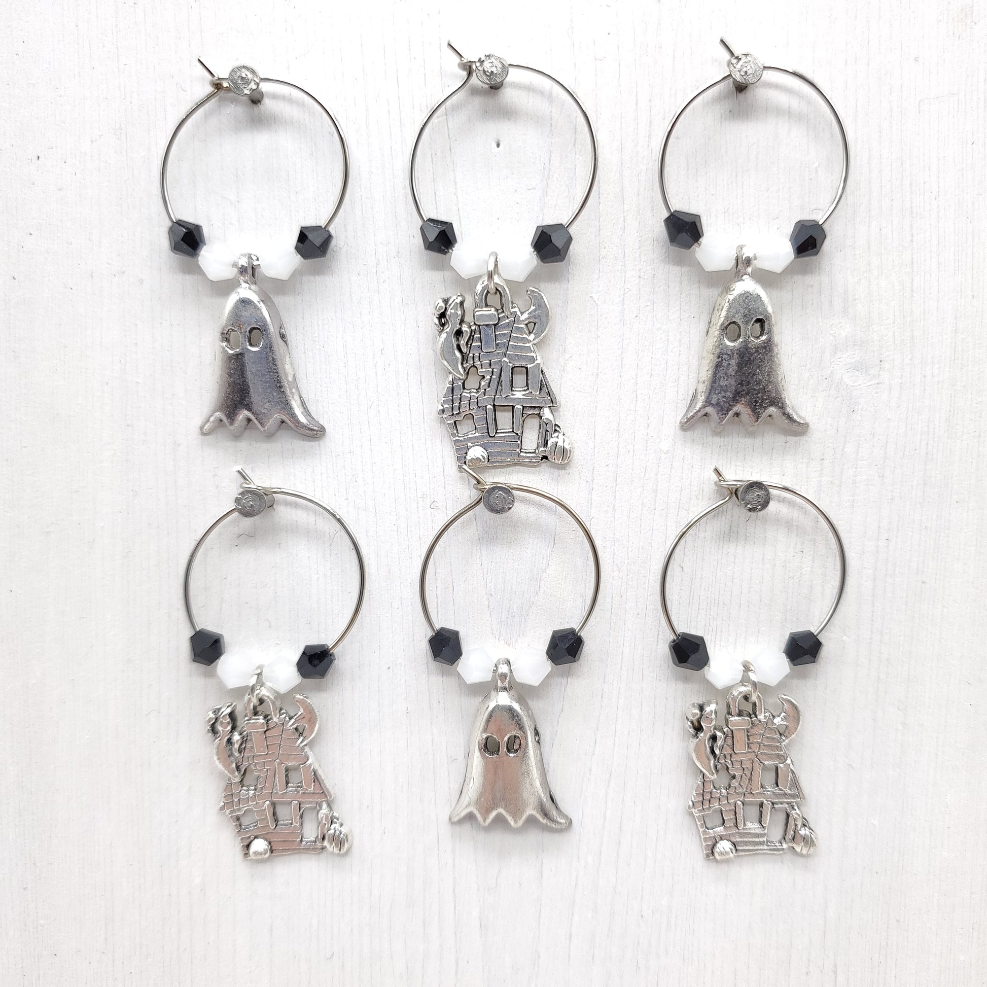 Set of silver wine glass charms with various designs, and with white and black beads on a white background
