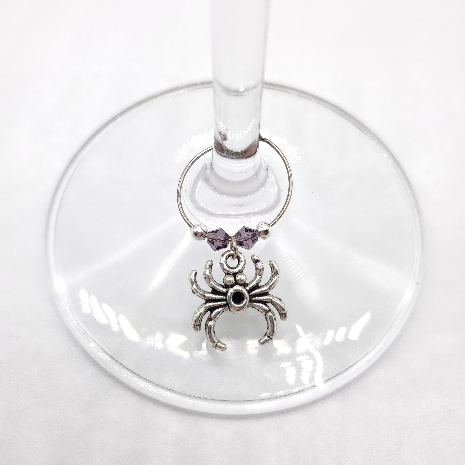 Wine glass charm with spider design on a white background