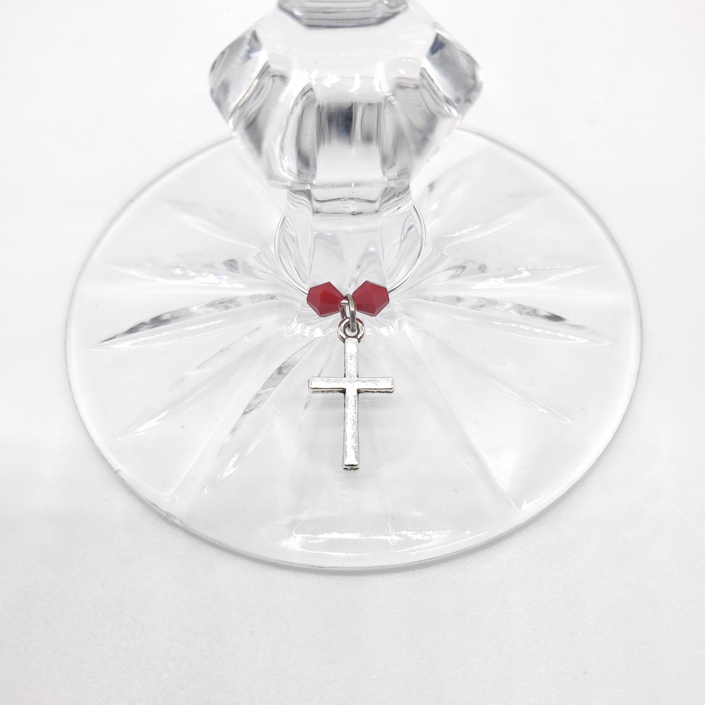 cross wine charm on a glass with red beads